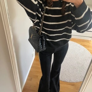 Svartvit randig stickad tröja - Säljer en svart stickad tröja med vita horisontella ränder. Tröjan har en avslappnad, lite oversized passform och långa ärmar med ribbade muddar. Perfekt för dig som gillar en chill och trendig look.