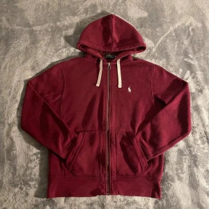 Vintage Polo Ralph Lauren Zip Hoodie - Säljer en vintage Zip Hoodie från Polo Ralph Lauren i vinröd. Den är sparsamt använd och i mycket bra skick. Varan kommer i storleken S, men är ganska liten i storleken, i och med det passar den utmärkt för de som är 170. Om du har några frågor så tveka att inte höra av dig. Pris går att diskuteras