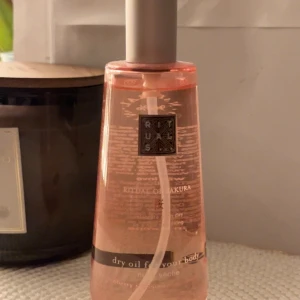 Rituals The Ritual of Sakura Dry Body Oil - Rituals The Ritual of Sakura Dry Body Oil med doft av körsbärsblom och risextrakt. Kommer i en elegant, genomskinlig rosa glasflaska med silvrig pump. Oljan är lätt och absorberas snabbt, perfekt för att ge huden en silkeslen känsla och lyster. Helt oanvänd 