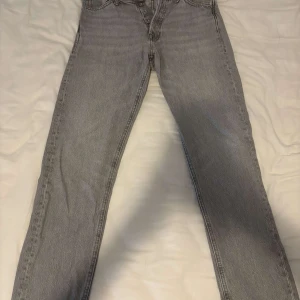 Grå loose fit jeans Jack & Jones - Grå jeans från Jack & Jones i loose fit-modell Chris. Klassisk femficksdesign, raka ben och knappgylf. Snyggt ljusgrå tvätt och tillverkade i bomull. Perfekta för en avslappnad och trendig look. Storlek W27 L32