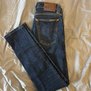 Mörkblå jeans från Nudie Jeans W26 L32 - Riktigt snygga Nudie jeans i sjukt bra skick! Jeansens nyans gör att dom matchar till allt. Storlek 26/32. Säljer dom för endast 299kr! Nypris cirka 1600kr.