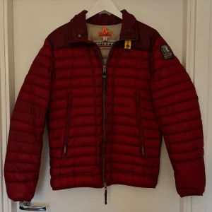 Röd pufferjacka från Parajumpers - Säljer en snygg röd pufferjacka från Parajumpers, modell Day Tripper. Jackan har quiltad design, dragkedja framtill och cool gul detalj vid kragen. Insidan är beige med meshficka och patch. Perfekt för dig som vill ha en varm och stilren jacka med streetkänsla.