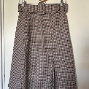 Rutig kjol med bälte  - Snygg och preppy kjol från Gina Tricot i rutigt mönster. Kjolen har ett brett bälte i midjan och klassisk A-linjeform. Perfekt för dig som gillar retrovibbar. Stl 38 men liten i stl, tajt över höfterna, midjemått 72 cm, skulle säga att den passar s/m. Sparsamt använd. 