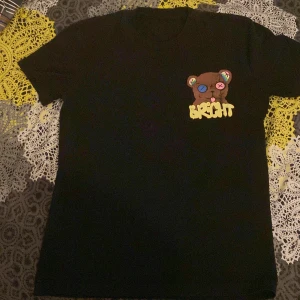 Svart Barrow t-shirt med björntryck - Svart t-shirt från Barrow med stort färgglatt tryck av en björn på ryggen och mindre björntryck med texten 'Bright' på bröstet. T-shirten har korta ärmar och en normal passform. Perfekt för dig som gillar streetwear och unika prints.