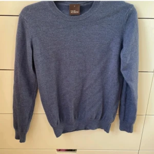 Blå stickad tröja från Oscar Jacobson - Säljer en snygg blå stickad tröja från Oscar Jacobson. Storlek: S men passar XS. Riktigt stilren tröja i 100% merinoull.