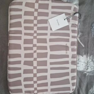 Mönstrad datorväska från WOSH - Stilren datorväska från WOSH med unikt grafiskt mönster i beige och ljusbrun. Väskan har mjuk vaddering och dragkedja längs kanten. Perfekt för att skydda din laptop med en snygg touch. Den är inte använd och prislappen sitter fortfarande på. 