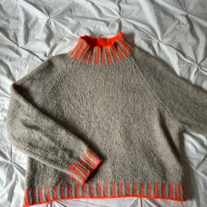 Stickad polotröja från Sweet Lover - Säljer en stickad polotröja från Sweet Lover, made in Italy. Tröjan är beige med coola orange detaljer vid krage, ärmslut och nederkant. Den har lång ärm och en hög, ribbad polokrage som sticker ut. Perfekt för dig som gillar unika plagg med färg. S/M