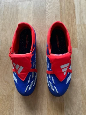 Adidas Predator Elite blå/röda fotbollsskor strl 38 2/3 AG - Snygga Adidas Predator Elites fotbollsskor i storlek 38 2/3. Endast använda 1 gång inga skador eller defekter. Säljer pga av att de var försmå. [Inget og tillkommer]. Nypris ca 3000 kr, skickar innan 24 timmar. Om du har någon fundering så är det bara att höra av sig 😃