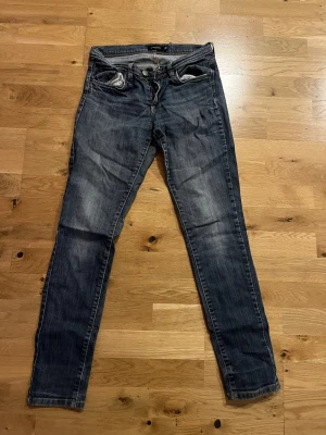 Mörkblå slim fit jeans - Säljer ett par mörkblå slim fit jeans med slitningar och tvättade detaljer längs benen.