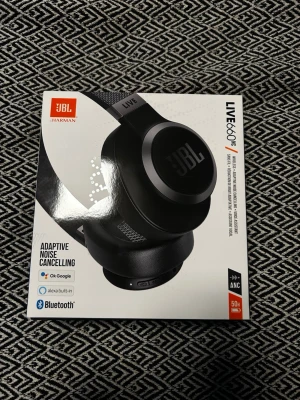 JBL LIVE660NC trådlösa hörlurar svart - JBL LIVE660NC är svarta over-ear hörlurar med adaptiv brusreducering, Bluetooth 5.0 och inbyggd röstassistent (Google/Alexa). De har mjuka öronkuddar, robust båge och upp till 50 timmars batteritid. Perfekta för musik, gaming och samtal.