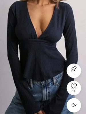 Svart v-ringad långärmad topp - Snygg marinblå topp med v-ringning och lång ärm. Modellen har en lätt utsvängd passform nedtill och ribbad struktur i tyget. Perfekt att styla med jeans eller kjol för en trendig look.