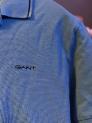 Blå pikétröja från Gant - Säljer en klassisk blå pikétröja från Gant med korta ärmar och krage. Andvänd ungefär 2-3 ggr ny pris 900kr