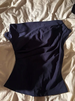 Mörkblå offshoulder festtopp - Snygg mörkblå offshoulder festtopp i stretchigt material. Toppen är figurnära och har en axelbandslös design som ger en trendig look. Perfekt att styla med jeans eller kjol för en cool outfit.
