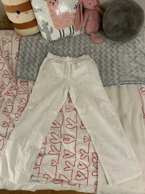 Vita linnebyxor från Gina tricot  - Säljer ett par vita linnebyxor med raka ben och resår i midjan. De är från Gina tricot. Byxorna har två fickor framtill och är tillverkade i linnematerial.
