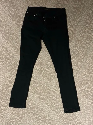 Svarta nudie jeans - Svarta skinny jeans från nudie med klassisk femficksdesign. Jeansen har smal passform hela vägen ner och är tillverkade i stretchigt material för extra komfort. Perfekta för en clean och stilren look.
