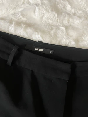 Svarta kostymbyxor från BikBok - Snygga svarta kostymbyxor från BikBok i stl 40, sista bilden visar lite slitage. Klassisk rak passform som funkar till många olika stilar. 