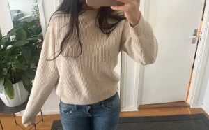 Stickad tröja  - Säljer en beige ribbstickad tröja med rund hals och långa ärmar. Tröjan har en avslappnad passform och är tillverkad i ett mjukt, tjockare material som passar perfekt för kyligare dagar. Enkel och stilren design utan synligt märke. NOPPRIG 