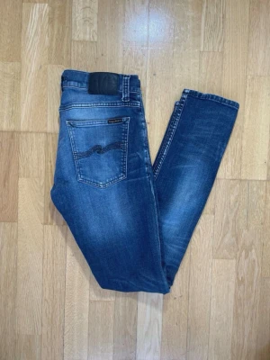 Washed jeans från Nudie - Snygga blå jeans från Nudie (Tight Terry) och diskret slitning på benen. Jeansen har en mörkblå tvätt och Nudie-logga på bakfickan. Perfekta för en avslappnad och trendig look.