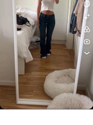 Mörkblå bootcut jeans - Säljer ett par mörkblå bootcut jeans med klassisk femficksdesign och normal midja. Jeansen har en snygg passform som sitter tajt upptill och släpper ut vid benen. Perfekta för en trendig och avslappnad look.