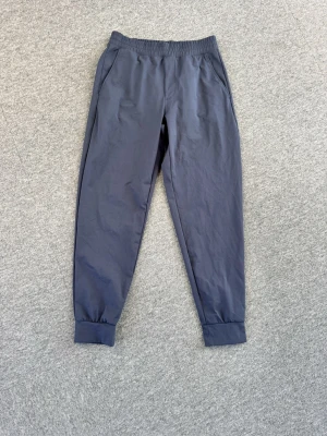 Mörkblå mjukisbyxor med resår - Mörkblå Uniqlo mjukisbyxor med elastisk midja och muddar vid bensluten. Byxorna har sidofickor och en bakficka med dragkedja. Perfekta för en avslappnad och chill stil. Tillverkade i mjukt och bekvämt material.