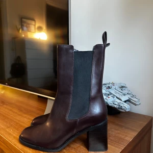 Helt nya skor - chelsea boots med klack - Snygga mörkbruna chelsea boots från & Other Stories. Supersnygg färg och design, har bara aldrig kommit till användning för mig. Obs det finns ett litet märke på insidan av ena skon (se bild 5) Nypris:1600kr