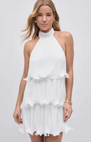 Vit omlott kortklänning med volanger - Säljer en vit kortklänning med halterneck och flera lager volanger. Klänningen har en omlott-look och är ärmlös, perfekt för sommarens alla tillfällen. Materialet känns lätt och luftigt, och volangerna ger en extra touch av stil.