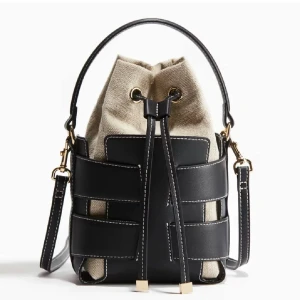 Svart och beige bucketväska med snörning, h&m inspererad - Snygg bucketväska i svart skinn och beige bomullstyg. Väskan har coola kontrastsömmar, snörning upptill och både handtag och axelrem med guldfärgade detaljer. Perfekt storlek för det viktigaste och ger en trendig vibe till din outfit.
