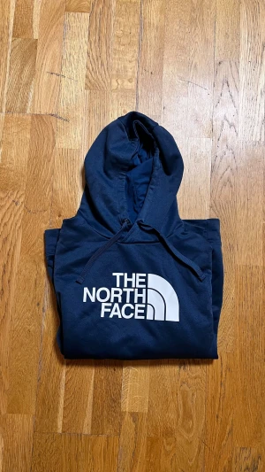 The North Face mörkblå hoodie - Snygg mörkblå hoodie från The North Face med stor vit logga på bröstet. Tröjan har snörning, långärmade ärmar och en klassisk känguruficka framtill. Perfekt för chill eller när du vill ha en enkel streetstyle-look. Nyskick. PRIS går att diskutera vid snabb affär 🤝 tveka inte att fråga vid minsta lilla