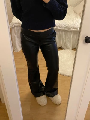 Skinnbyxor Bershka - Säljer ett par svarta bootcut skinnbyxor från Bershka i storlek S. Säljer då de är för långa på mig som är 163, på bild 5 och 6 syns de slitningar som blivit på byxorna nederkant. 