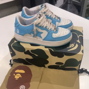 Blå och vita Bape skor - Säljer nu mina skor då det inte används mer, det är i bra skick förutom att vänster sulan är lite sliten. Om du vill ha med låda, påse och sticker går de på 50kr mer .                                                                                       Pris kan diskuteras