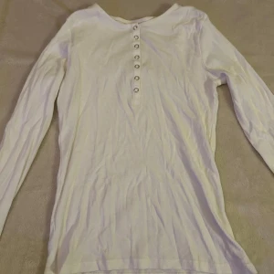 Vit långärmad tröja  - Säljer en vit långärmad tröja från Lindex i storlek S. Tröjan har knappar framtill och är gjord i ett väldigt skönt material. Enkel, snygg och bekväm att ha på sig.🩷