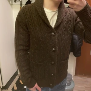 Brun stickad cardigan - Otroligt fet brun stickad cardigan med mönster. Perfekt nu till kallare väder. Modellen är 180cm, 74kg. Priset går såklart att diskuteras!