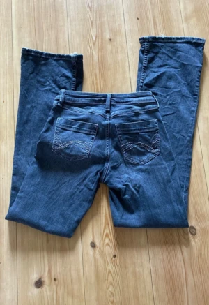 Gråsvarta jeans från Divided - Säljer dessa gråsvarta lågmidjade/midwaist bootcut jeans då jag tycker de är lite för pösiga på mig. Använda ett fåtal gånger! Jeansen har blivit lite slitna längst ner men inget som märks tydligt! Snygga fickor 