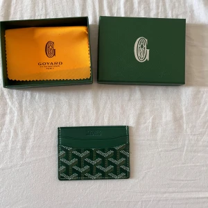 G-plånbok  - Snygg och stilren i grön  med deras ikoniska mönster. Plånboken har flera kortfack och är tillverkad i skinn med tryckt logga framtill. Perfekt för dig som vill ha något exklusivt och smidigt i fickan.  