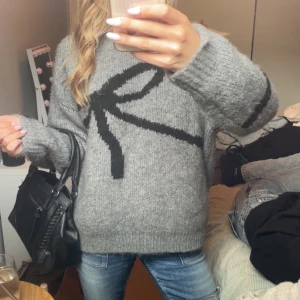 Grå stickad tröja med svart rosett från cider - Supermysig grå stickad tröja från cider som knappt är använd