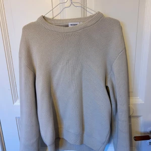 Beige stickad tröja från Weekday - Säljer en stilren beige stickad tröja från Weekday i storlek XS. Tröjan har en klassisk rund halsringning och långa ärmar. Perfekt för lager-på-lager och enkel att matcha med olika outfits.