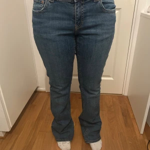 Blå bootcut jeans från Perfect Jeans - Snygga blå jeans från Perfect Jeans i storlek 42. Modellen har bootcut-ben, hög midja och klassiska fickor med lock bak. Jeansen är i ett mjukt denimtyg med lite stretch och har en tidlös blå tvätt. Perfekta för dig som gillar en bekväm och trendig look.