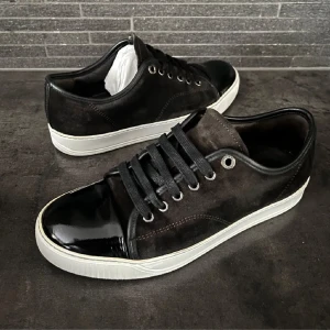 Svara Lanvins  - Snygga svarta sneakers med ovandel i mocka och glansig lackad tå. Skorna har svarta snören, silverfärgade öljetter och vit platt sula. Perfekt för dig som gillar en stilren men ändå unik look! Skriv gärna vid frågor 