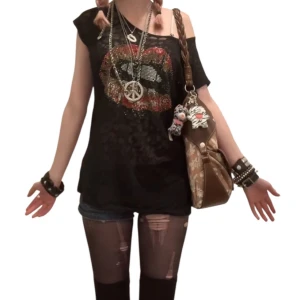 Svart t-shirt med paljettläppar - Svart t-shirt i tunn bomull med ett stort läppmotiv i paljetter på bröstet. T-shiten går att bära off shoulder och är kortärmad, med lätt transparent tyg och coolt leopardmönster i bakgrunden. Perfekt för dig som gillar edgy och unik stil. 