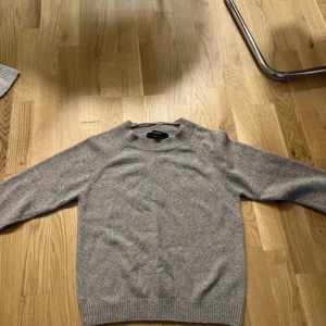 Grå stickad tröja från Vero Moda - En stilren grå stickad tröja från Vero Moda  i mjuk ullmix. Tröjan har rund halsringning, ribbade muddar och lång ärm. Perfekt för lager-på-lager och enkel att matcha med jeans eller kjol. #veromoda