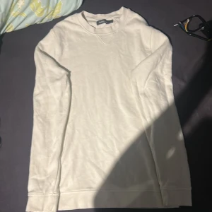 Vit långärmad  - En stilren vit långärmad tröja från Divided. Tröjan har en klassisk rund halsringning och är gjord i mjuk bomull, chill vardagsstil. Enkel design utan mönster eller detaljer, passar till allt.