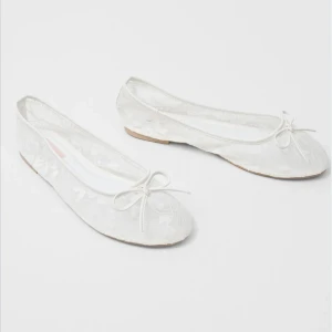 Vita spetsballerinaskor från Nelly - Söta vita ballerinaskor från Nelly med spetsdetaljer och rosett framtill. Skorna har rund tå och platt sula, vilket ger en klassisk och feminin look. Perfekta att styla med jeans eller klänning för en romantisk vibe. Säljer då de ej passade mig