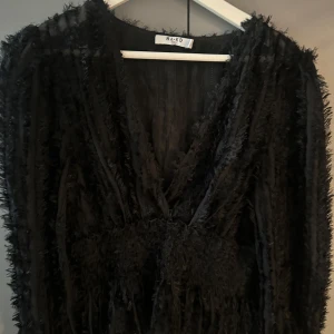 Svart blus - Svart blis från NA-KD med transparenta partier och fluffiga ränder. Djup v-ringning och markerad midja.