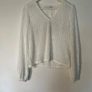 Vit strukturerad blus från Vila XS - Säljer en vit blus från Vila i storlek XS. Blusen har en snygg strukturerad yta, v-ringning och långa ärmar med lätt puff och resår vid ärmslut. Tunt och luftigt material som ger en fräsch känsla. Ny med prislapp! 