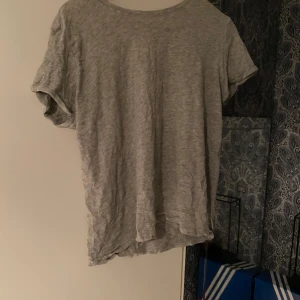 Grå basic t-shirt i bomull - Enkel grå t-shirt med rund hals och korta ärmar. T-shirten har en avslappnad passform och är tillverkad i mjuk bomull, perfekt för en chill och stilren look.