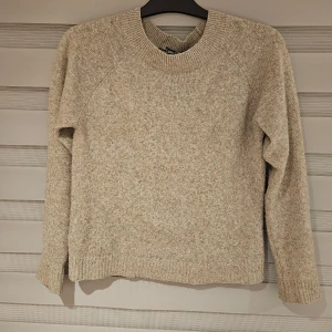 Beige stickad tröja från Vero Moda XS - Mysig beige stickad tröja från Vero Moda i storlek XS. Tröjan har rund halsringning, ribbade muddar och en klassisk, enkel design som är lätt att matcha. Perfekt för lager-på-lager under kyliga dagar.