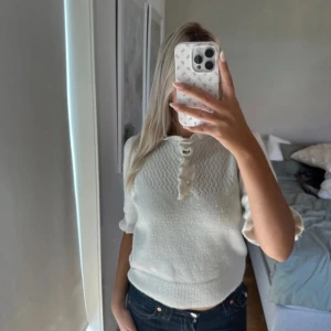 Vit stickad tröja med volangdetalj - Supersöt vit stickad tröja med korta ärmar och volangdetalj vid knäppningen framtill. Fina detaljer✨