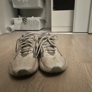 Gråvita golfskor från Puma - Säljer ett par snygga Puma sneakers i grått och vitt med coola detaljer och chunky sula. Skorna har snörning och är tillverkade i syntetmaterial och textil. Perfekta för dig som vill ha ett snygga golf dojor som passar bra i både golf och de mesta annat. Nypris 1300kr