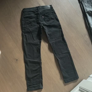 Svarta Levis 502 jeans taper - Svarta Levis 502 Regular Taper jeans med klassisk femficksdesign och röd Levis-tag på bakfickan. Jeansen har en avsmalnande passform och är tillverkade i mjukt jeansmaterial. Perfekta för dig som gillar stilrena och tidlösa svarta jeans.