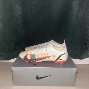 NIKE MERCURIAL VAPOR XIV ELITE FG White/Black/Bright Crimson/Pink Blast -  Säljer mina fotbollsskor som endast är använda två gånger på plan, vilket innebär att de fortfarande är i mycket bra skick. Ursprungligen köpte jag skorna mest som prydnad till rummet, men nu vill jag låta någon annan få användning av dem på riktigt.